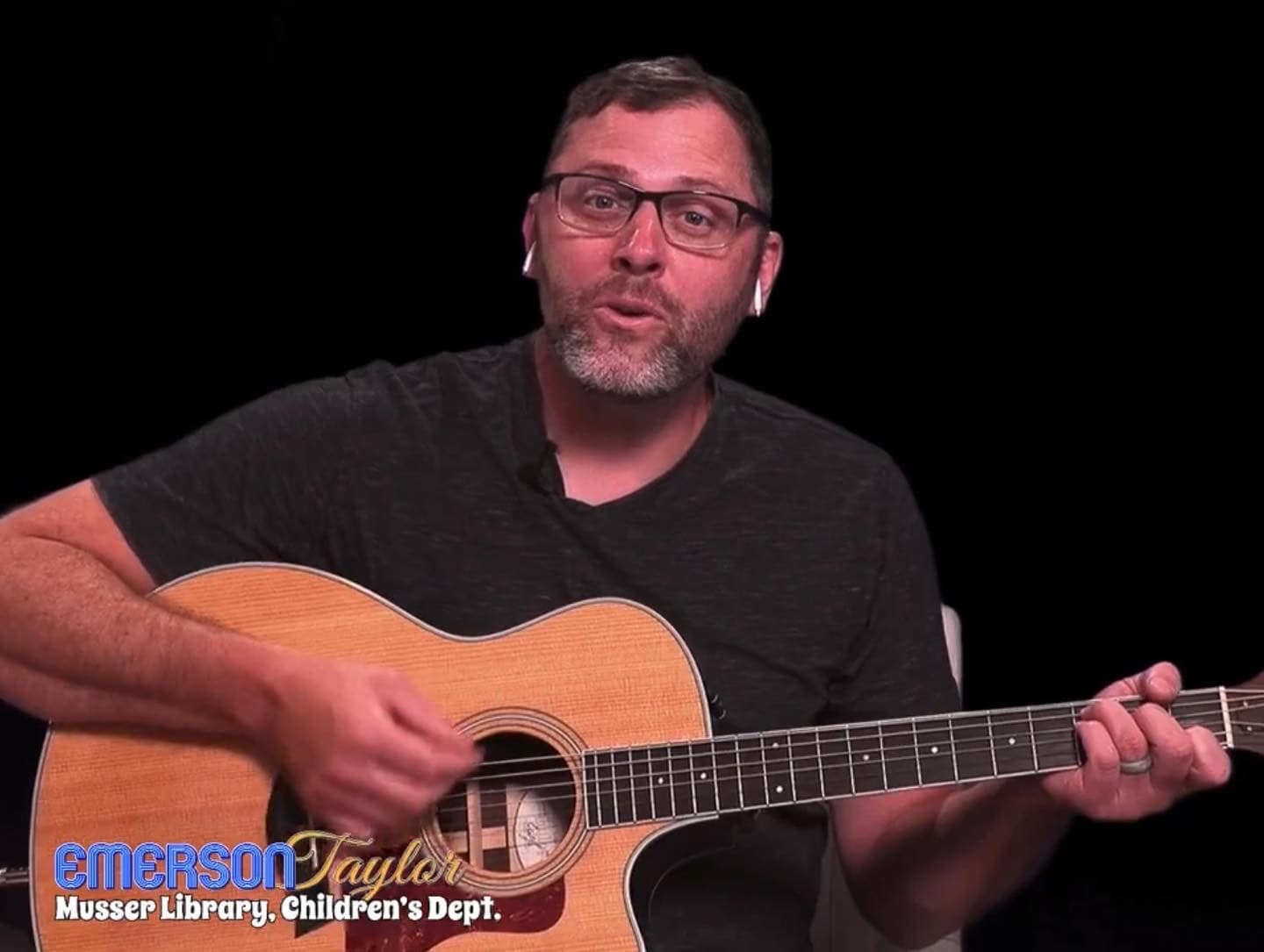 Emerson Taylor new Musser Library Children's Librarian playing guitar (JPG)